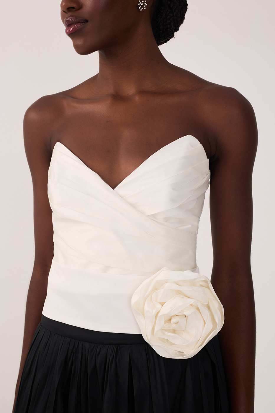 Close-up of white strapless sweetheart top with draped bodice and large fabric rosette at the waist