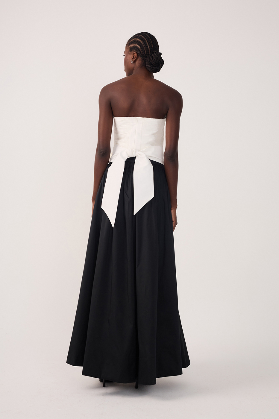 Full-length back view of white strapless bow-back top and black flowing maxi skirt