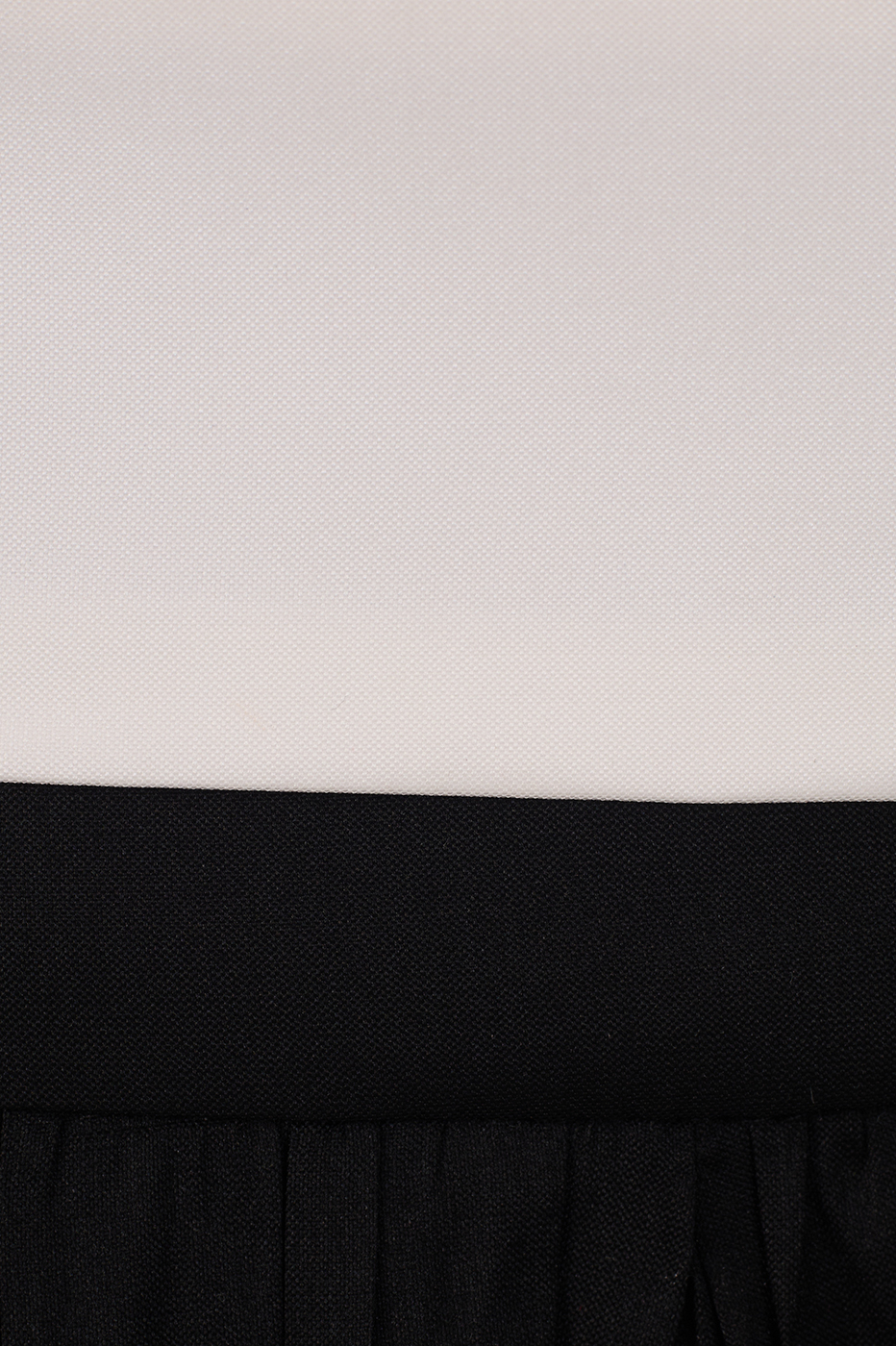 Fabric detail of white top meeting black gathered skirt at the waist