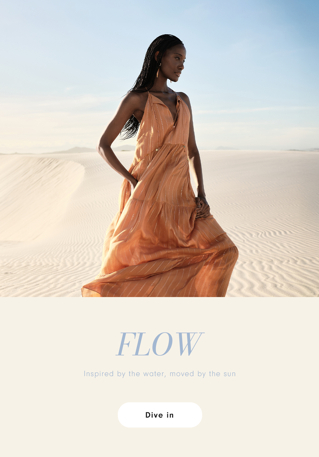 Woman wearing a long, flowing peach-colored dress, posing in a light sand dune landscape with a blue sky in the background. Banner from the "FLOW - Inspired by the water, moved by the sun" campaign with a "Dive in" button.