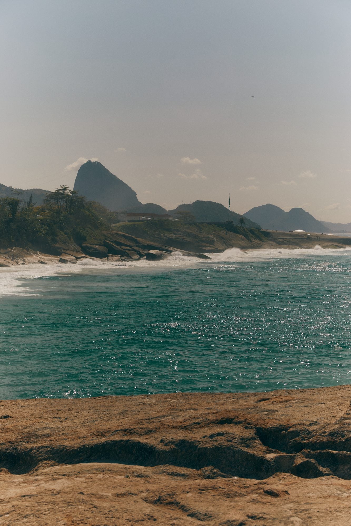 Rocks and turquoise sea along the Rio de Janeiro coast, mountains on the horizon