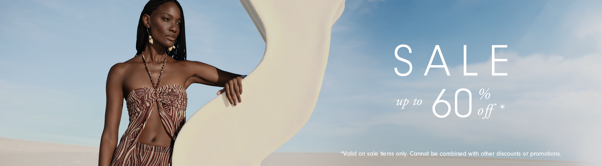 Wide sale banner: woman in a brown and cream printed strapless outfit on white sand dunes, with text Sale up to 60% off and a note that it is valid on sale items only