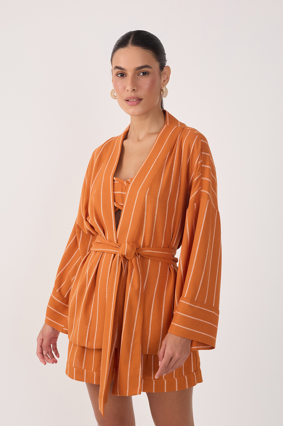Woman wearing a rust orange pinstripe belted kimono jacket with matching shorts set