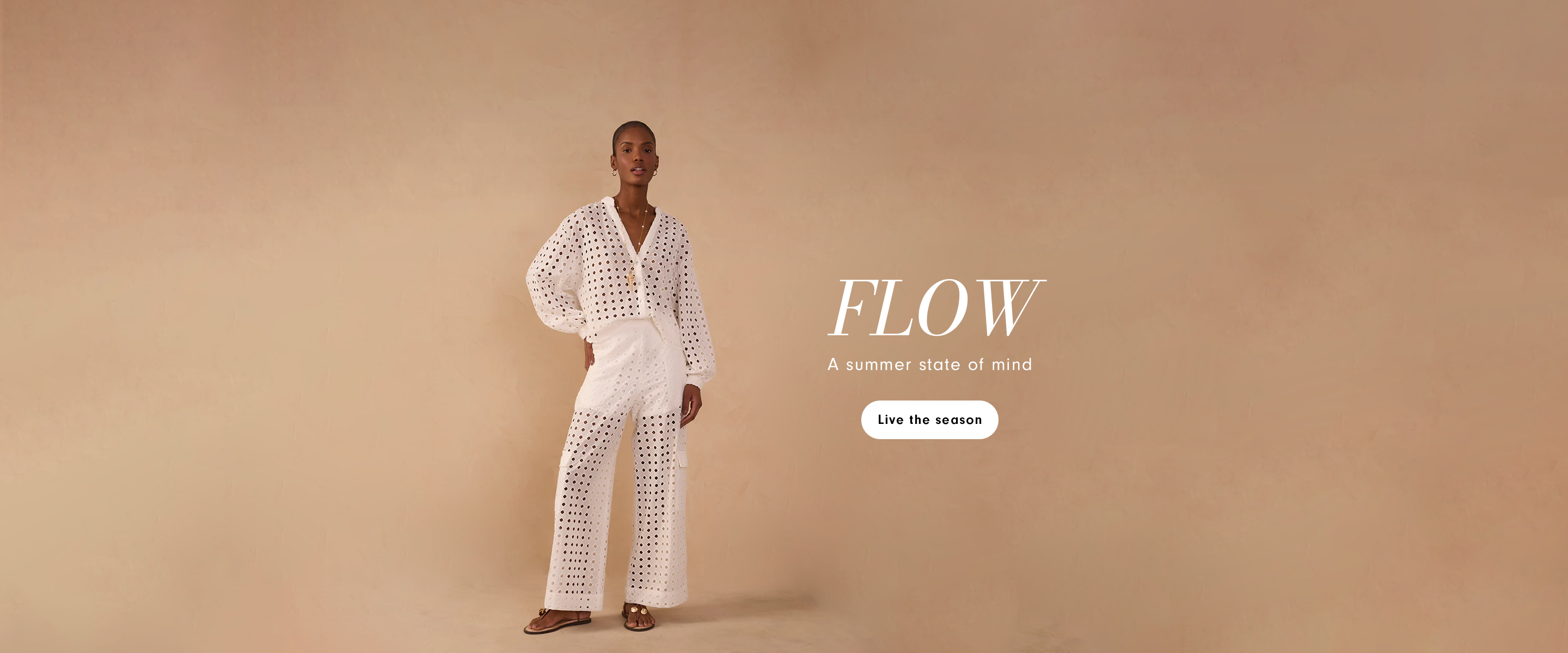 Desktop banner of a woman wearing a white eyelet broderie anglaise blouse and matching wide-leg pants, standing against a beige background. Text reads "Flow - A summer state of mind" with a "Live the season" button.