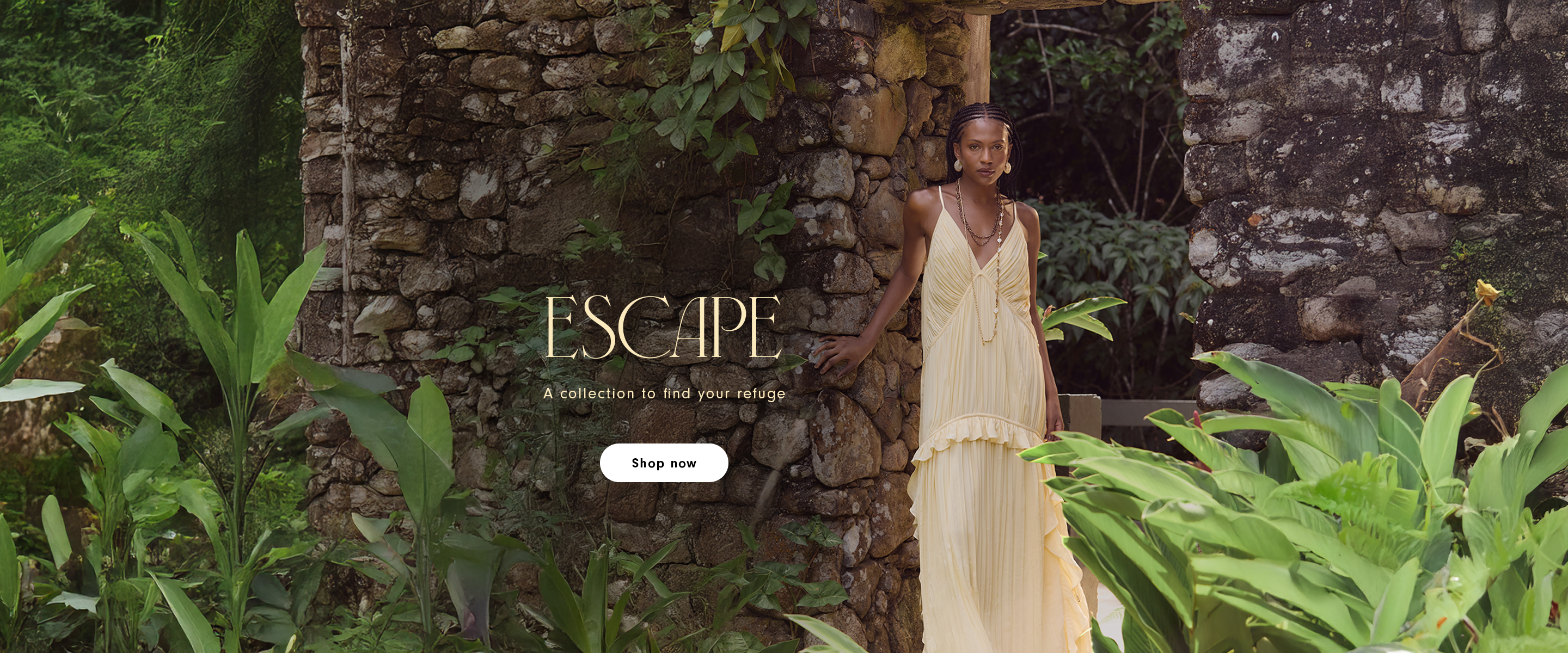 Escape collection desktop banner featuring a woman in a flowing yellow dress against an old stone wall surrounded by tropical foliage