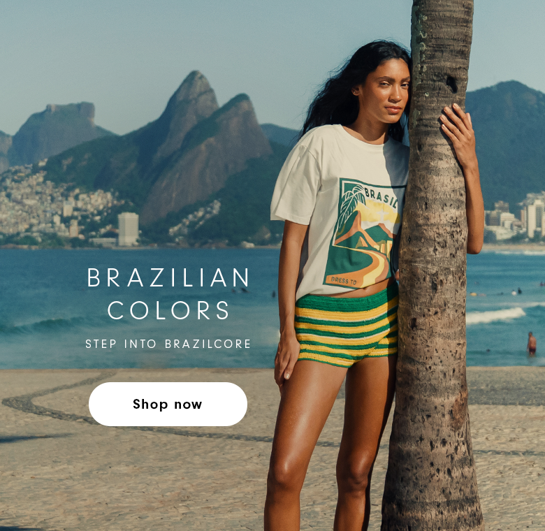Brazilian Colors banner - Step into Brazilcore - woman in white t-shirt and green and yellow striped shorts leaning against a palm tree on Ipanema beach with Two Brothers mountain in the background, Shop Now button