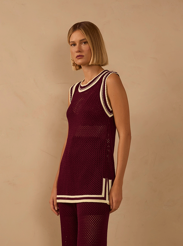 Shop by size XS banner: woman in a burgundy open-knit tank top and matching trousers with cream stripe trim against a beige backdrop