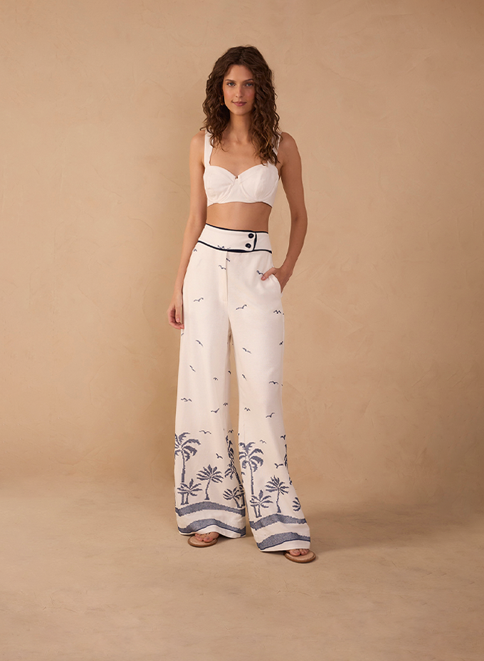 Model wearing white crop top and wide-leg pants with palm tree print - Bottoms category