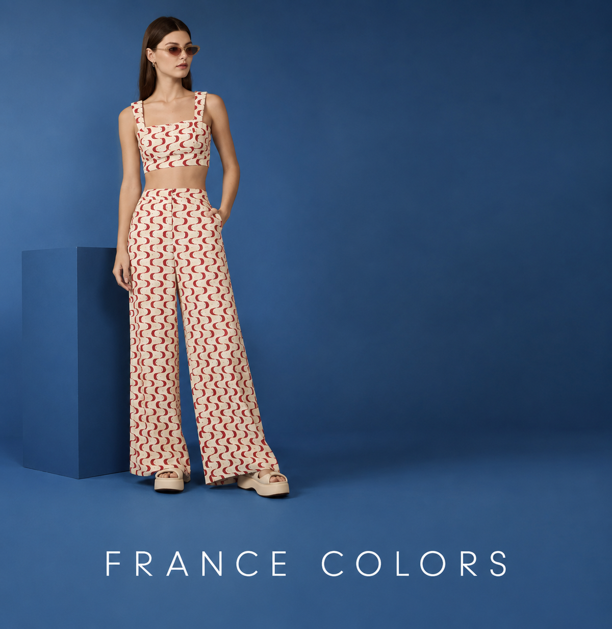 Woman wearing sunglasses and a printed crop top with matching wide-leg pants, standing against a blue background, with the text "France Colors"