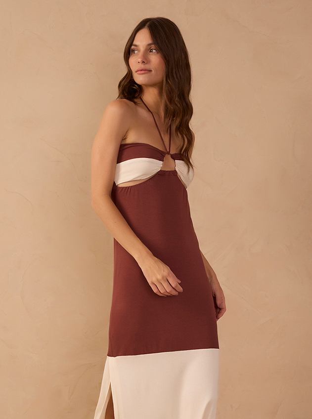 Woman wearing a brown halter-neck maxi dress with white cutout detail and ivory hemline