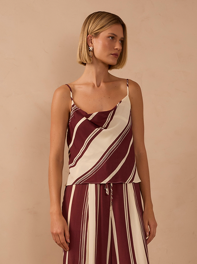 Blonde woman with a short bob wearing a burgundy and cream diagonal striped camisole and matching striped wide-leg trousers
