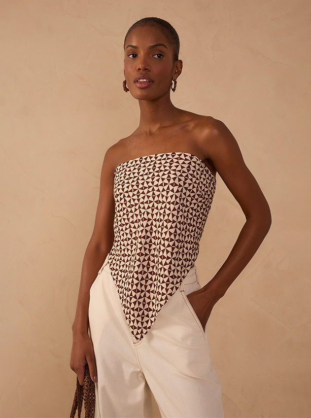 Woman wearing a strapless geometric triangle-print bodysuit with ivory wide-leg trousers