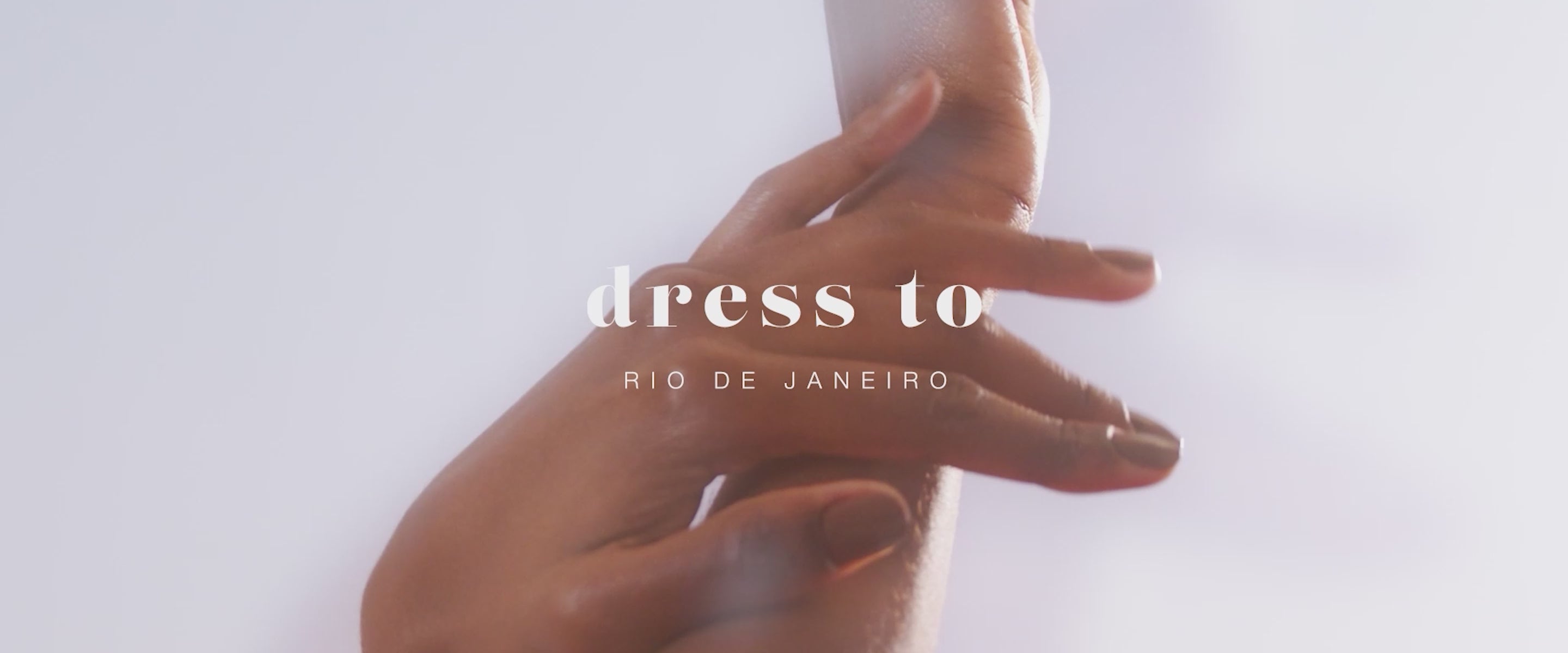 Home page desktop banner video: close-up of a woman's hands with the Dress To Rio de Janeiro logo on a light background